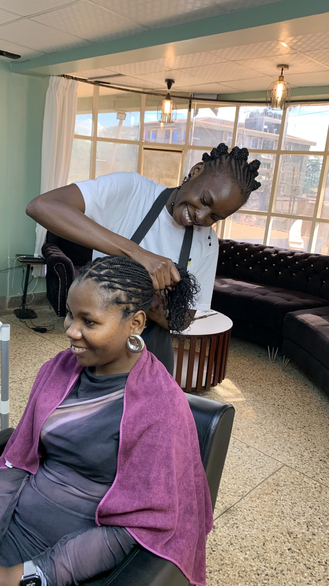 Stylist braiding a smiling client at Raquel Tresses
